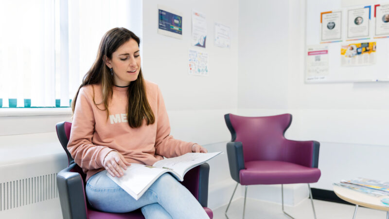 A woman reading a magazine in a reception area