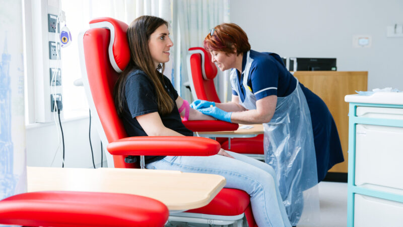 A nurse taking blood from a smiling patient