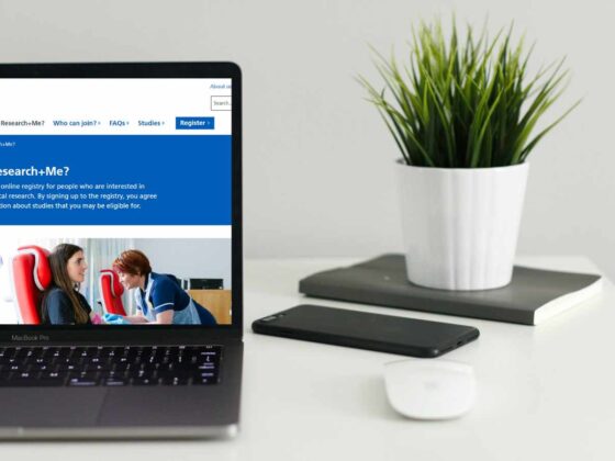 A laptop showing the Research+Me website on screen